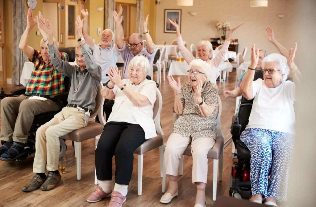 A group of seniors sitting in chairs at a community center chapping and cheering