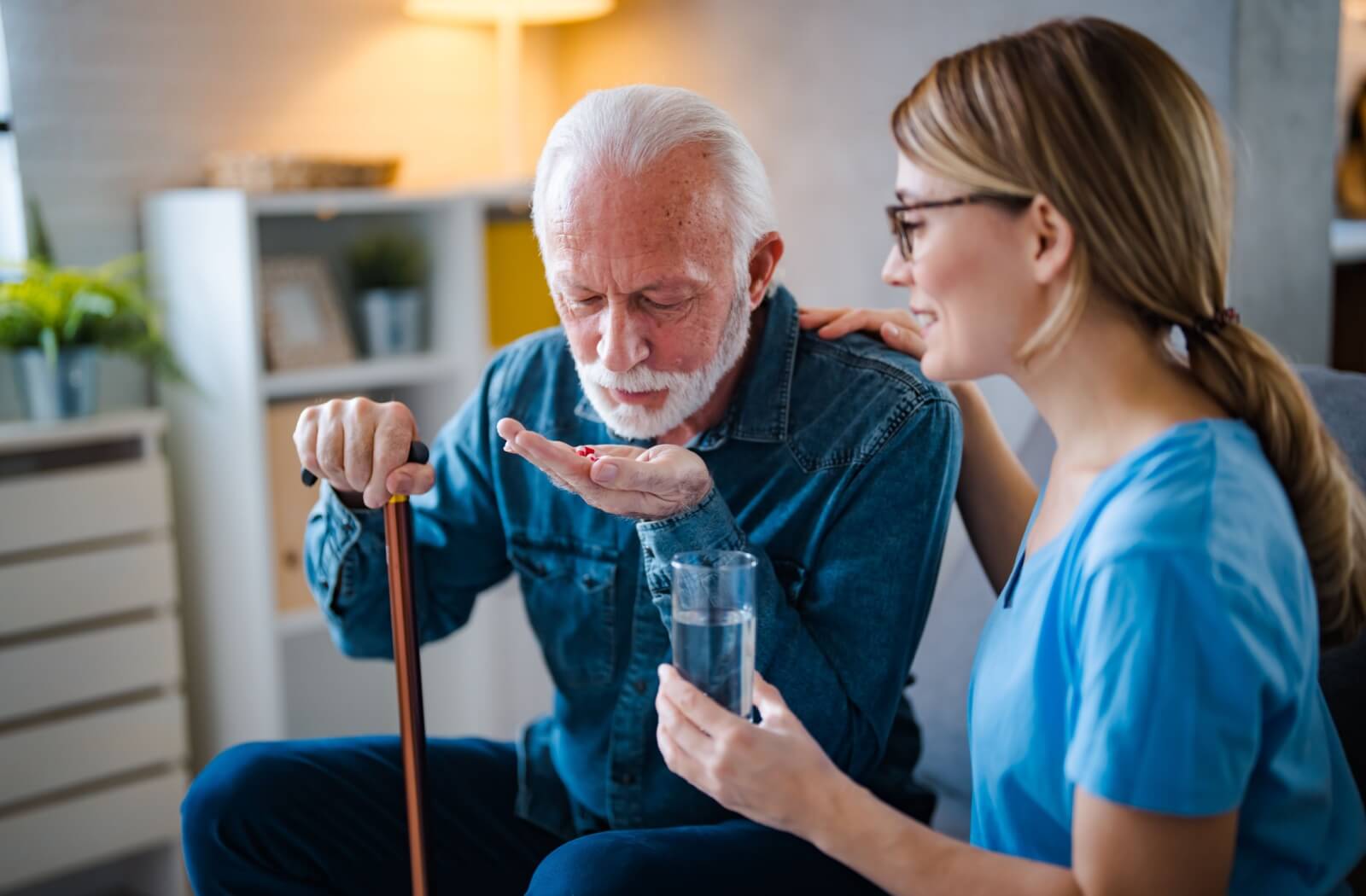 A professional caregiver assists a senior resident with their medications to ensure the proper dosage and timing.