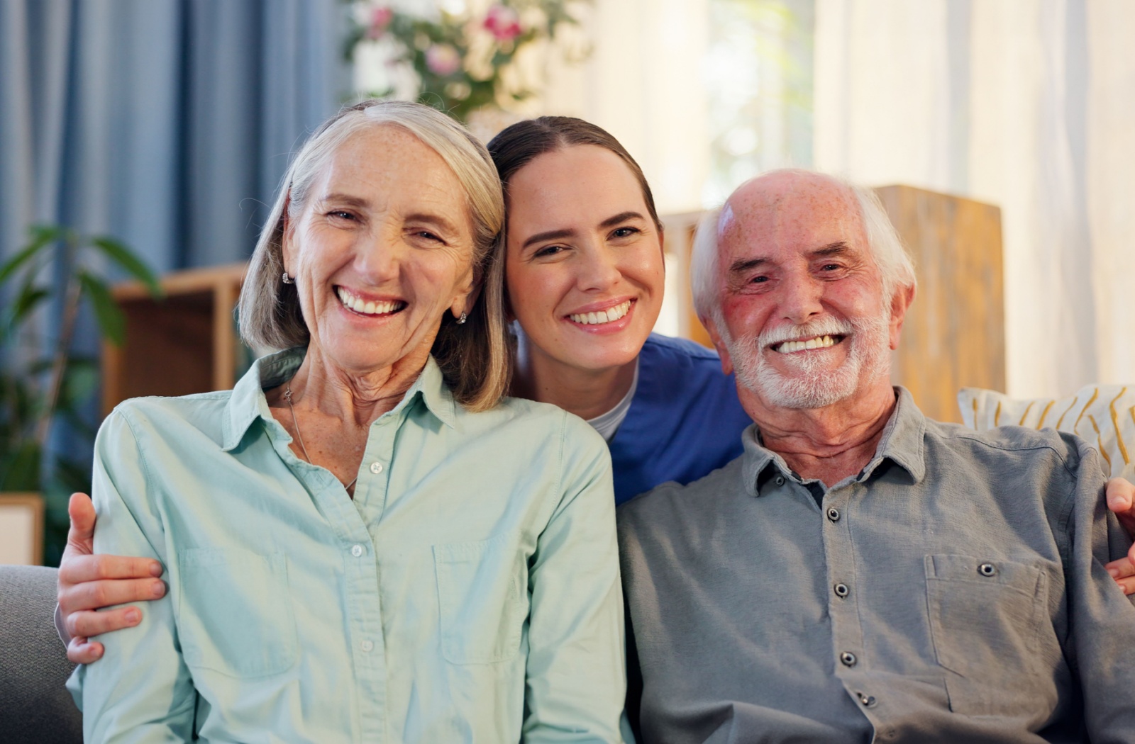 Caregiver posing with a happy elderly couple in assisted living.