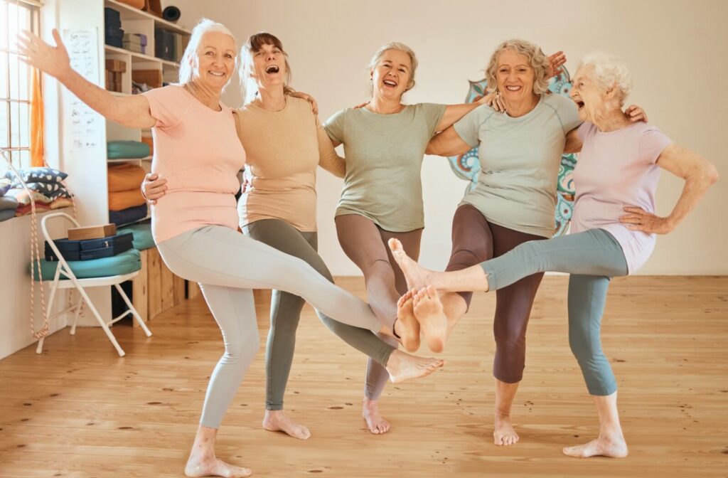 A group of happy seniors in assisted living celebrate after an exercise class.
