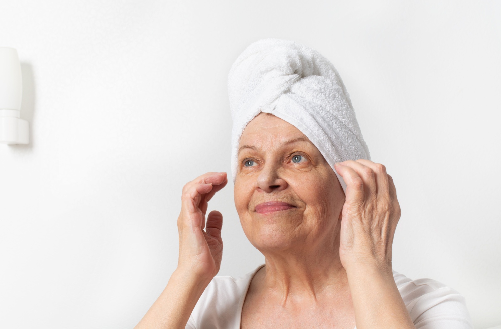 Older adult who just got out of the shower and is hearing a towel on her head.