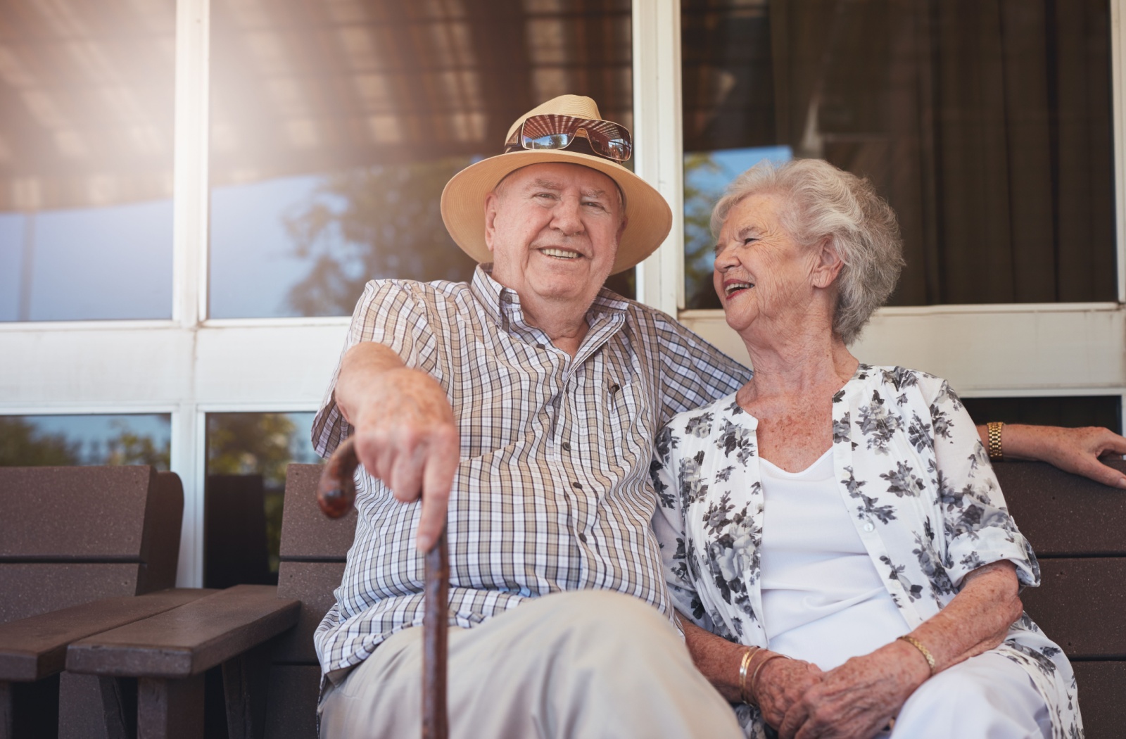 A senior couple sitting outside during the summer under a shaded area.