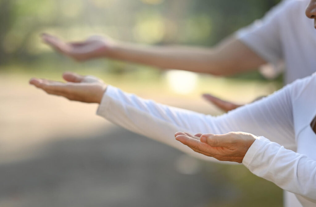 A pair of older adults performing tai chi exercises in the park to improve their balance.