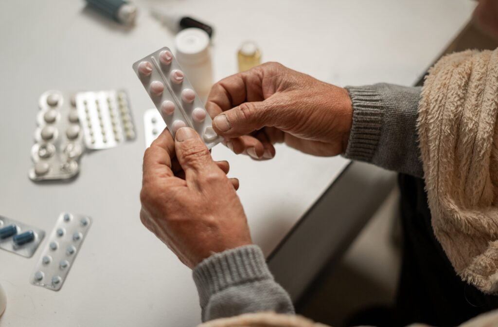 An elderly person holding a medication packet in their hands.